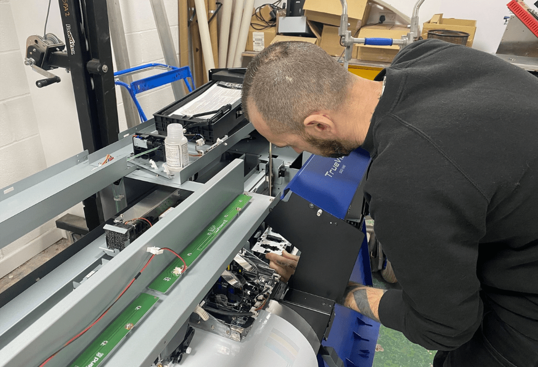 An employee performing maintenance on the LEC 540 Roland printer. 